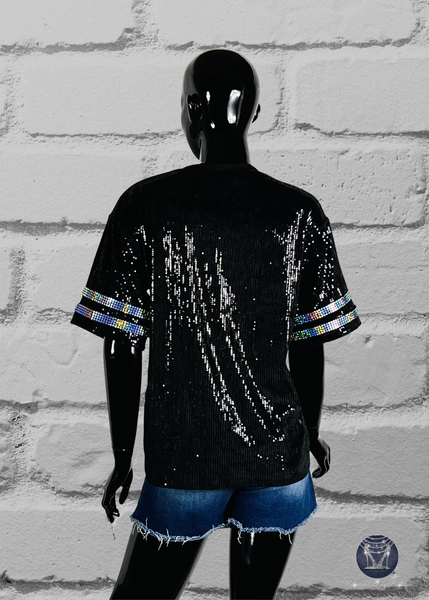 Black custom football-style sequin jersey shown from the front view with  striped bling silver sleeve accents, displayed on a black mannequin against a white brick wall.
