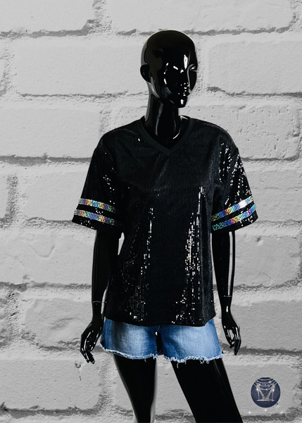 Black custom football-style sequin jersey shown from the front view with  striped bling silver sleeve accents, displayed on a black mannequin against a white brick wall.