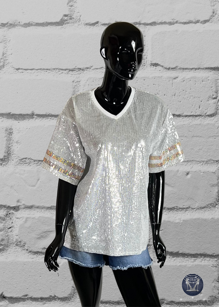 White custom football-style sequin jersey shown from the front view with  striped bling gold sleeve accents, displayed on a black mannequin against a white brick wall.
