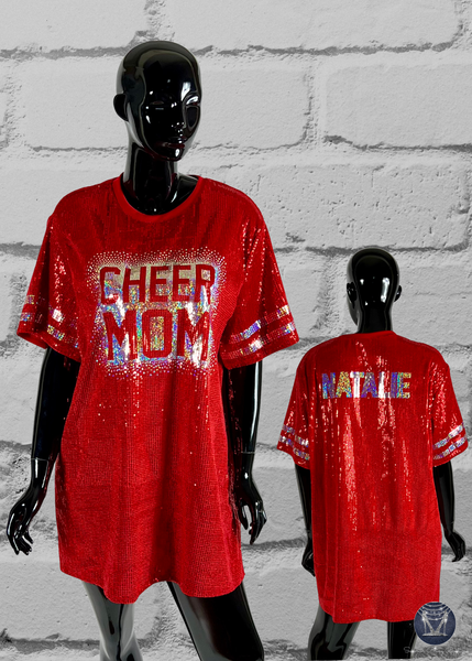 Red sequin dress with 'CHEER MOM' text on front and 'Natalie' on back, worn by mannequins against a gray brick wall.