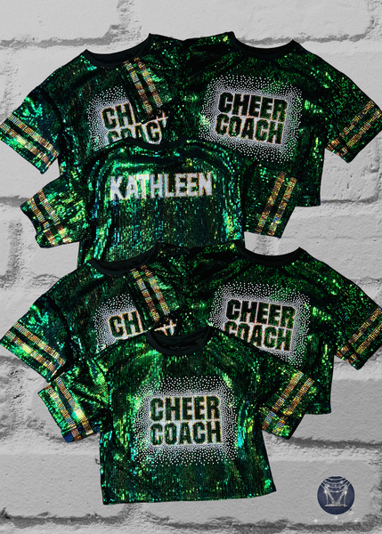 Green sequin jerseys with 'CHEER COACH' on front and custom text on back in holographic white and gold spangle bling on a brick wall background